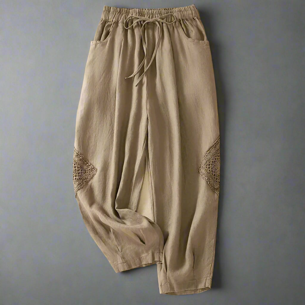 Beige pants with lace details on a beige background with shoes and text.