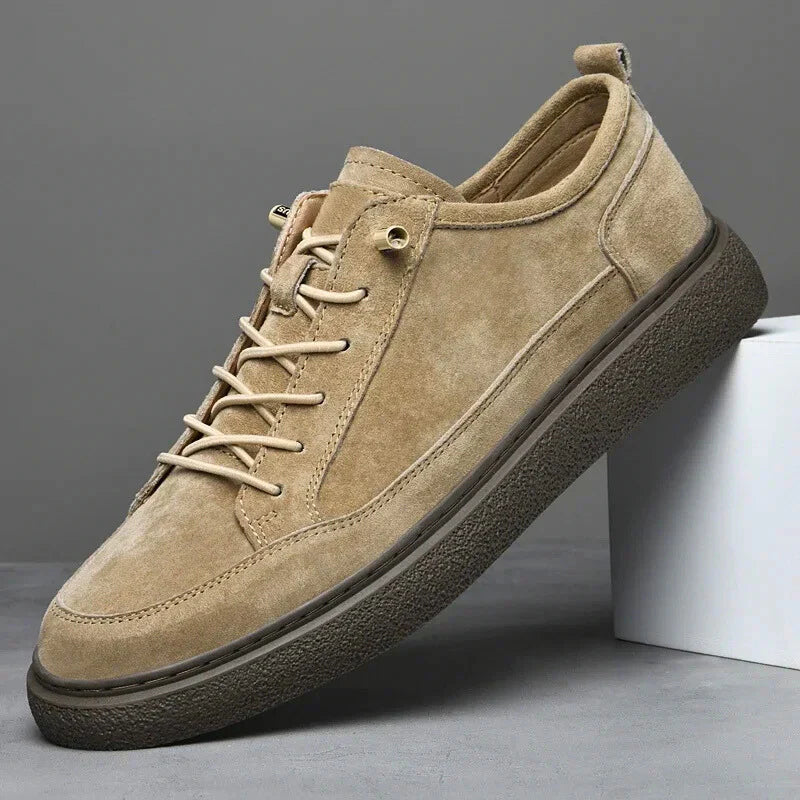 Beige suede sneaker with a black sole on a gray background