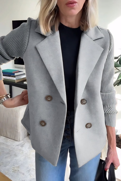 Person wearing a gray peacoat with a blurred indoor background