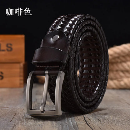 Brown woven leather belt with silver buckle on a wooden surface