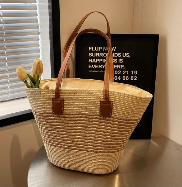 Woven basket with brown handles on a surface near a window