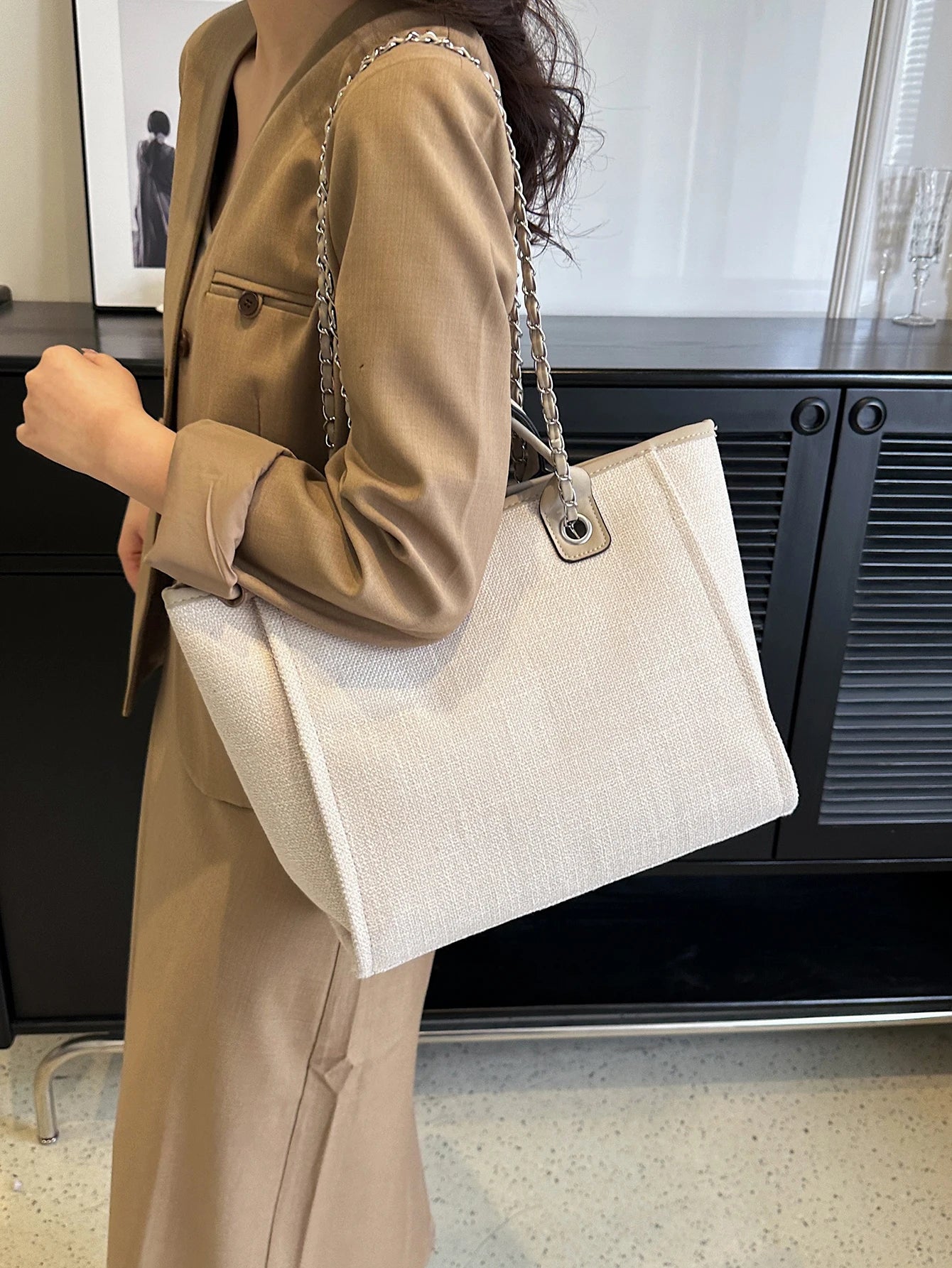 Person holding a beige tote bag in an indoor setting