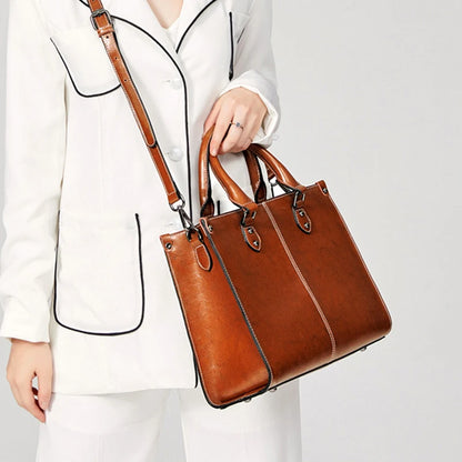 Brown handbag held by a person wearing a white outfit on a light gray background