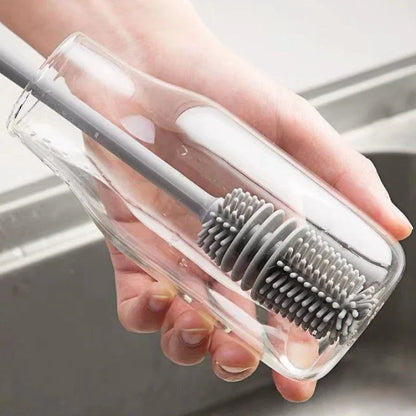 Hand holding a clear plastic case with a gray bristle brush over a sink.