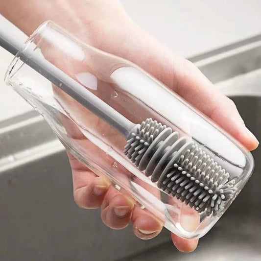 Hand holding a clear plastic case with a gray bristle brush over a sink.
