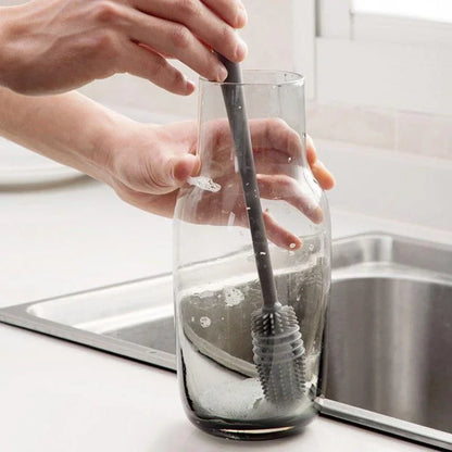 Person cleaning a glass with a brush in a kitchen setting