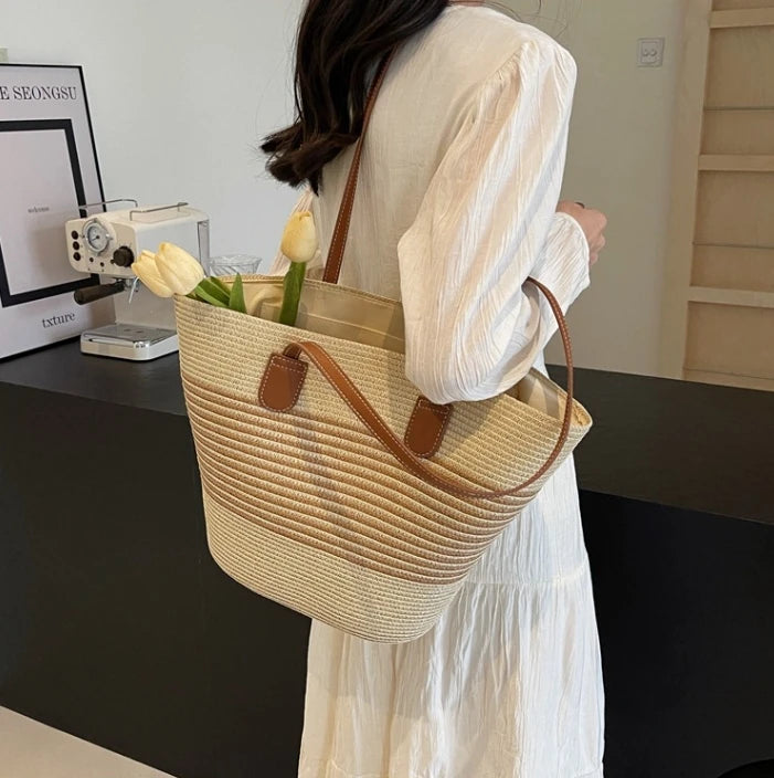 Person holding a woven tote bag with flowers indoors