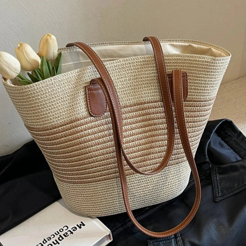 Woven handbag with brown handle and trim, containing tulips, on a dark surface.