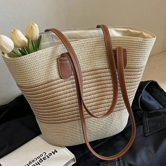 Woven handbag with brown handle and trim, containing tulips, on a dark surface.