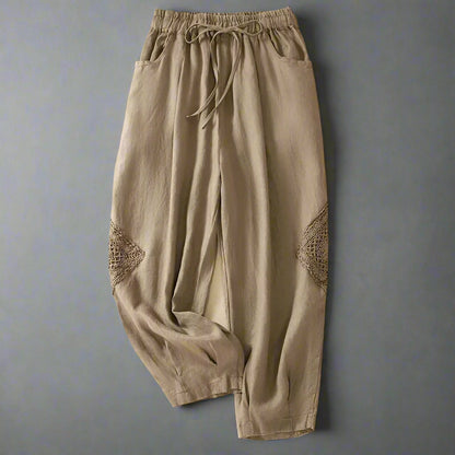 Beige pants with lace details on a beige background with shoes and text.
