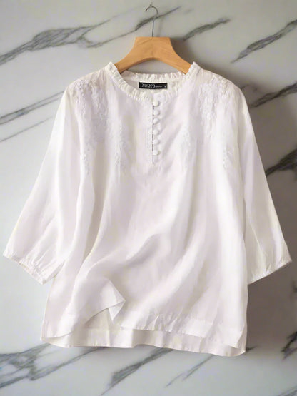 White blouse on a hanger with ZANZEA branding against a beige background