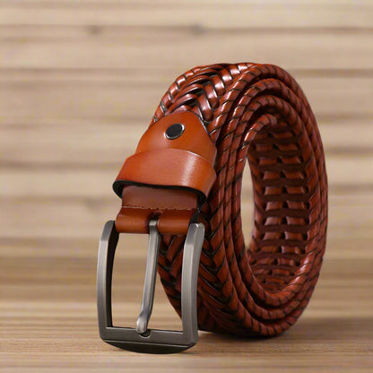 Brown woven belt with metal buckle on a wooden surface